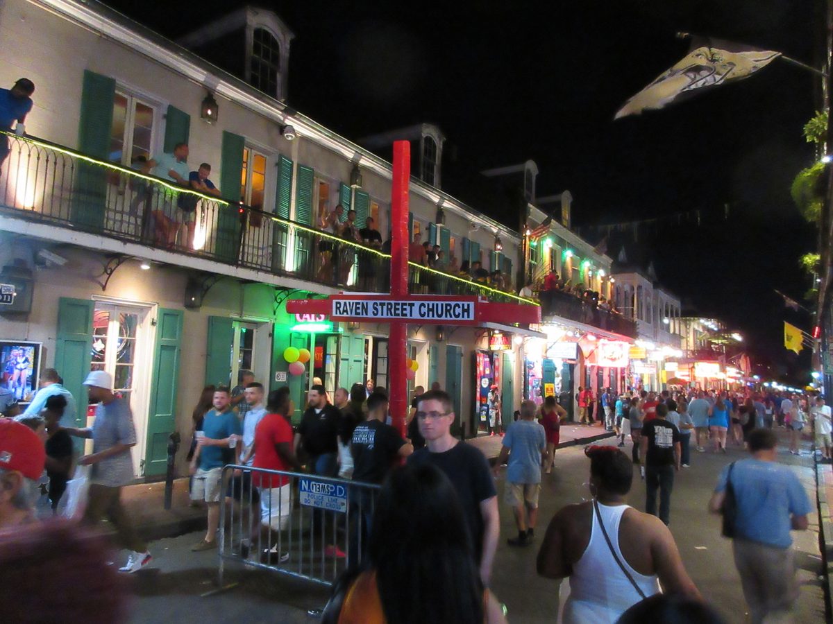 Bourbon Street at night in the French Quarter of New Orleans, neon-lit bars and crowds visible.
